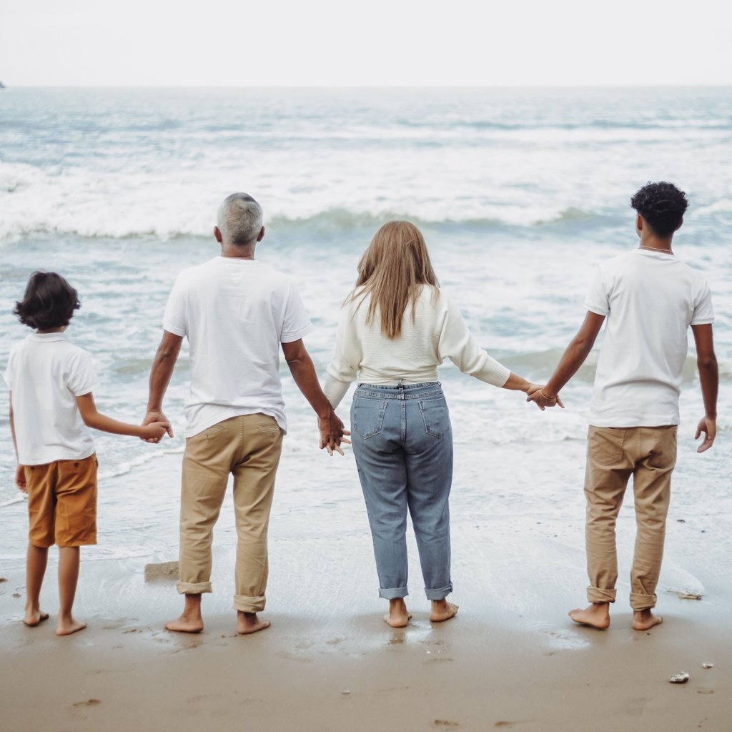 A family holding hands together at the beach, looking out to the sea